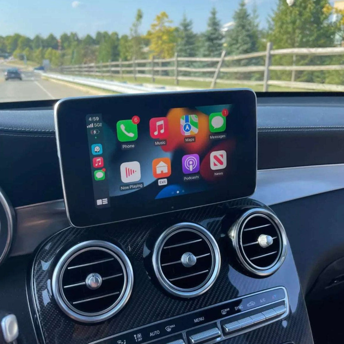 Mercedes-Benz C-Class interior showing the integrated wireless CarPlay interface on the infotainment screen while driving.