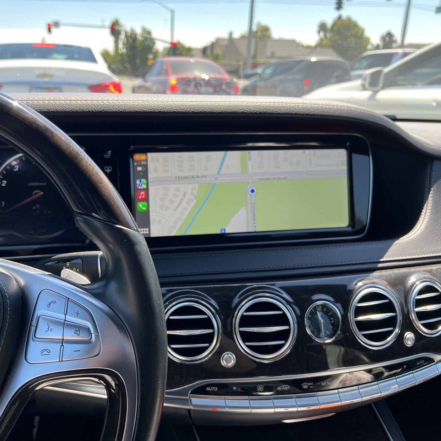 Mercedes-Benz W222 steering wheel view with the integrated wireless CarPlay system displayed on the car's screen.